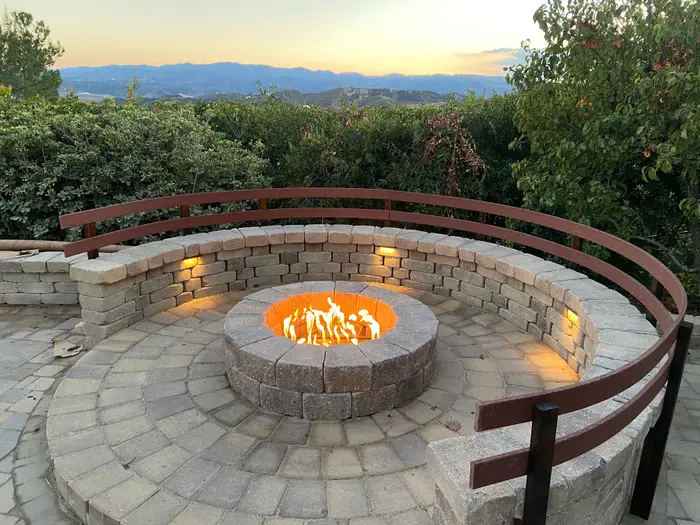Round fire pit with curved stone seat wall at sunset