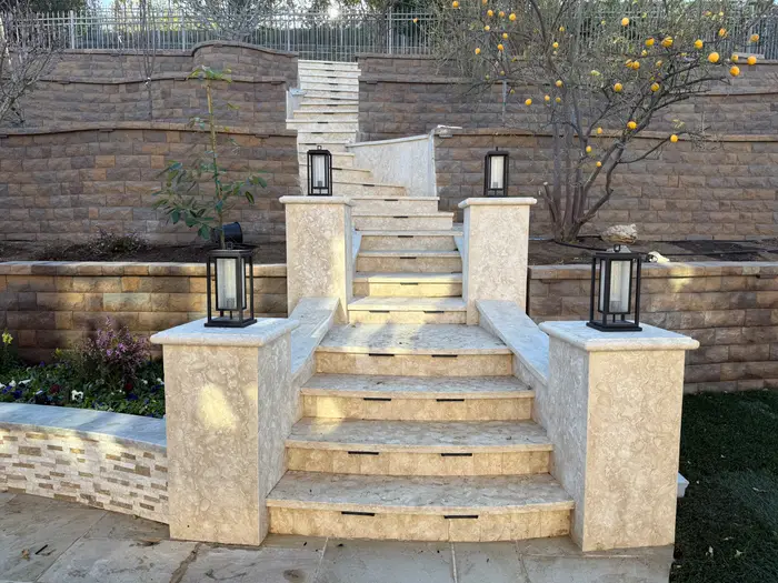 Travertine stairs with lit pillars between retaining walls