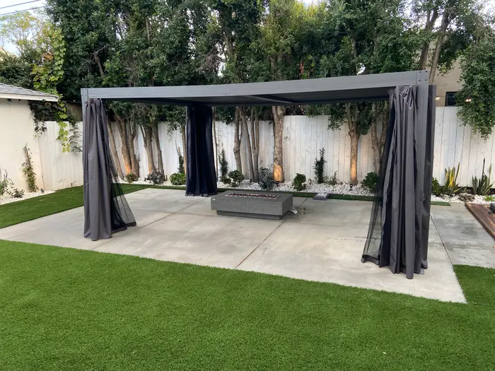 Pergola with curtains over a seating area on turf